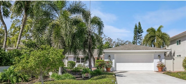 view of front of house featuring driveway, an attached garage, fence, and stucco siding