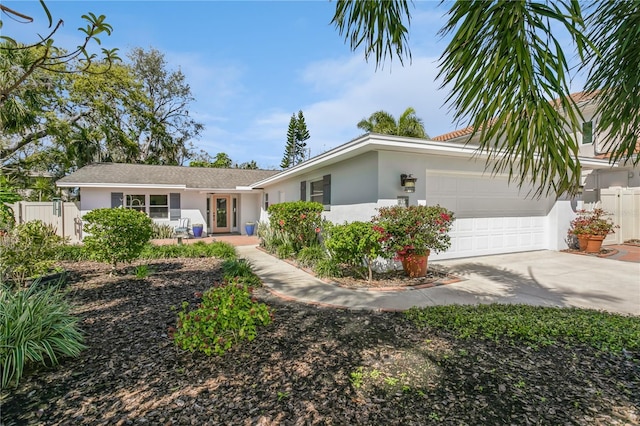 ranch-style home featuring an attached garage, driveway, fence, and stucco siding