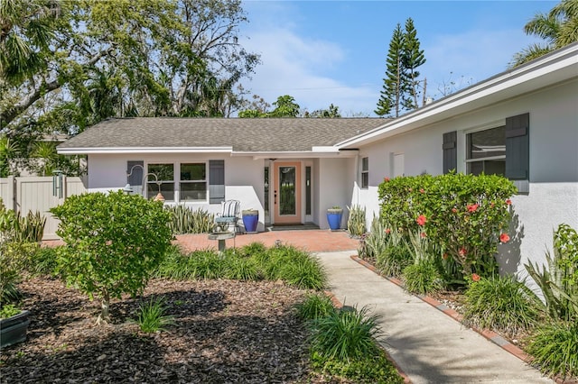 doorway to property featuring fence and stucco siding