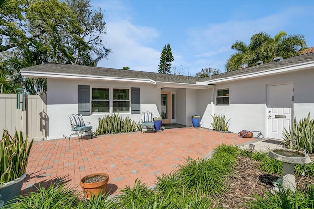 view of front facade with fence, a patio, and stucco siding