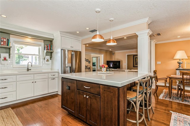 kitchen with decorative columns, visible vents, a sink, and stainless steel fridge with ice dispenser