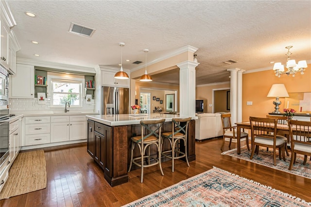 kitchen with decorative columns, stainless steel appliances, light countertops, open shelves, and a sink