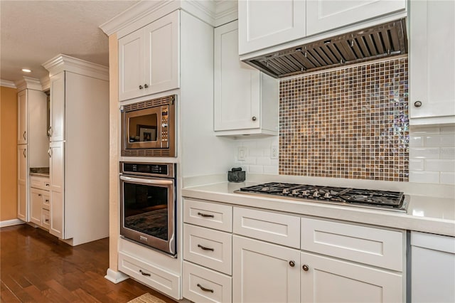 kitchen featuring light countertops, appliances with stainless steel finishes, white cabinetry, and range hood