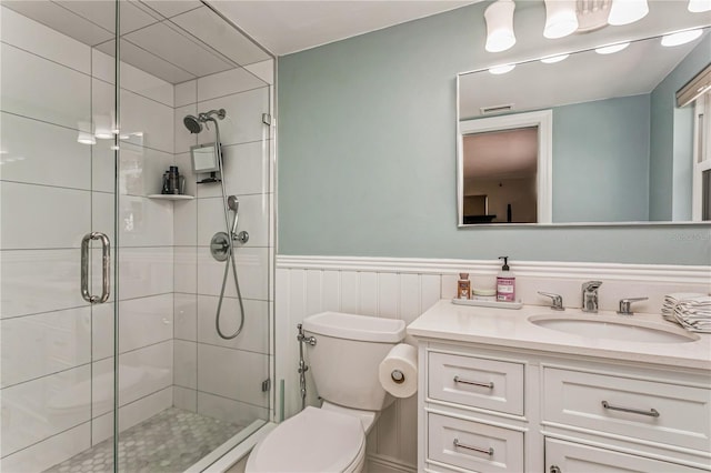 full bathroom with toilet, visible vents, vanity, wainscoting, and a shower stall