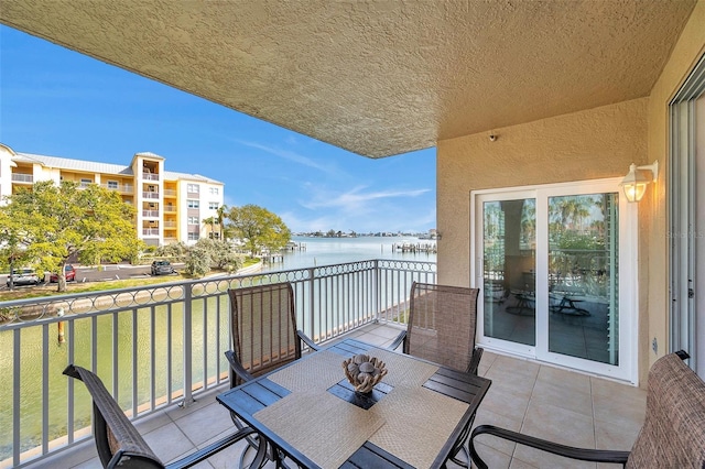 balcony with outdoor dining space and a water view