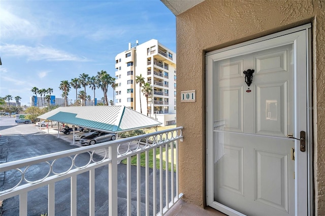 property entrance featuring covered parking, a balcony, and stucco siding