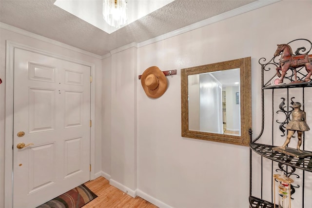 entryway with ornamental molding, a textured ceiling, baseboards, and wood finished floors