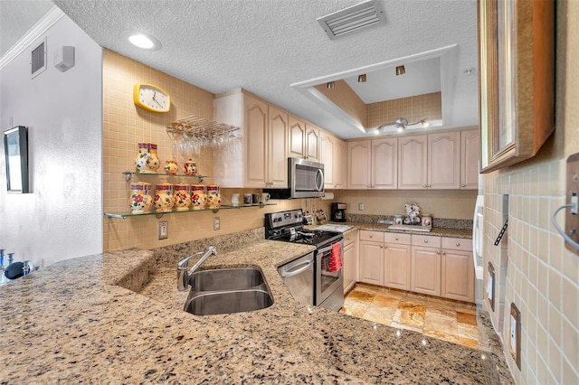 kitchen with light stone counters, stainless steel appliances, a raised ceiling, visible vents, and a sink