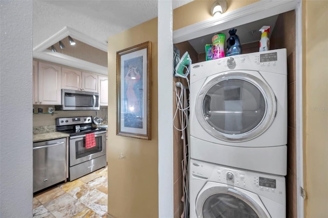 clothes washing area with laundry area, a textured ceiling, and stacked washer / dryer