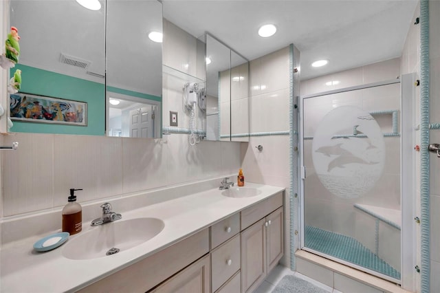 full bathroom with double vanity, a stall shower, and a sink