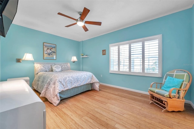 bedroom with a ceiling fan, baseboards, wood finished floors, and ornamental molding