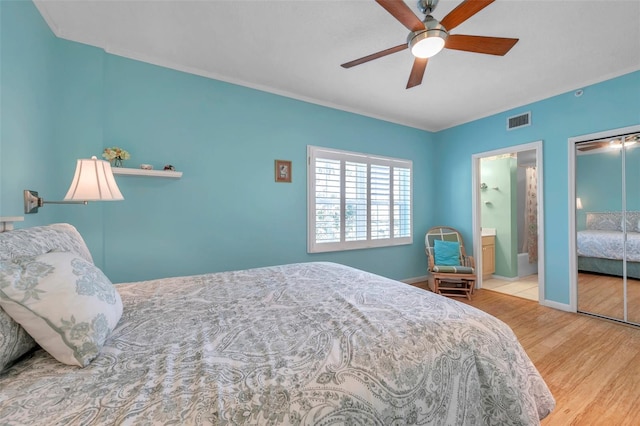 bedroom featuring visible vents, a ceiling fan, connected bathroom, wood finished floors, and baseboards