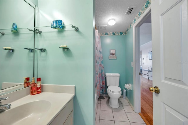 bathroom with a textured ceiling, toilet, tile patterned flooring, and visible vents