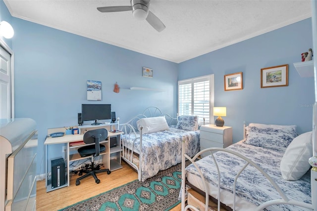 bedroom featuring crown molding, a textured ceiling, ceiling fan, and wood finished floors