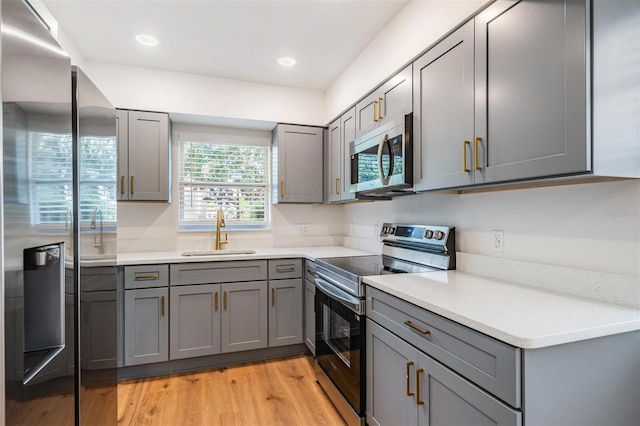 kitchen featuring sink, gray cabinets, stainless steel appliances, and light wood-type flooring