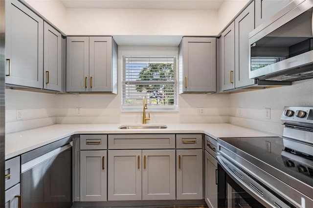 kitchen with gray cabinetry, sink, and stainless steel appliances