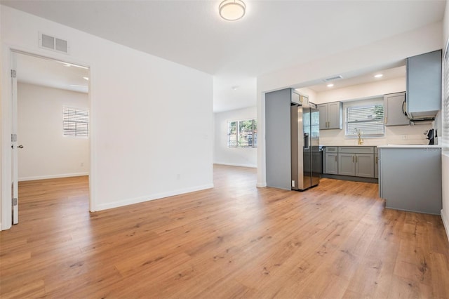 kitchen featuring gray cabinetry, sink, stainless steel fridge, and light wood-type flooring