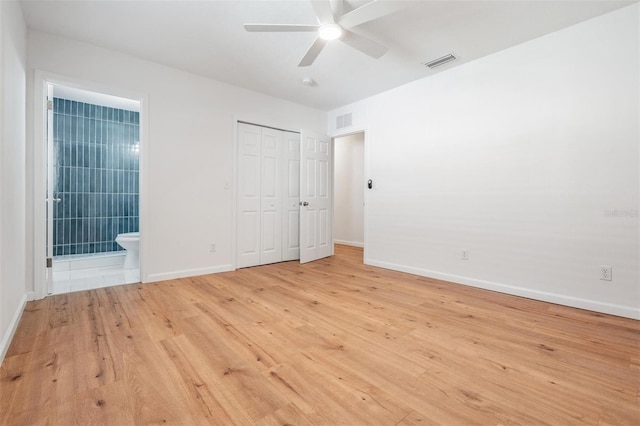 unfurnished bedroom with ensuite bathroom, a closet, ceiling fan, and light hardwood / wood-style flooring