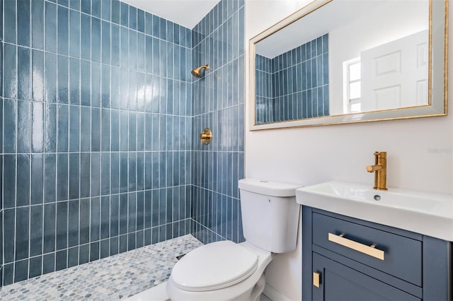 bathroom featuring tiled shower, vanity, and toilet