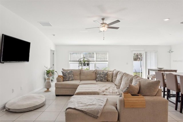 living area with light tile patterned floors, visible vents, a healthy amount of sunlight, and a ceiling fan