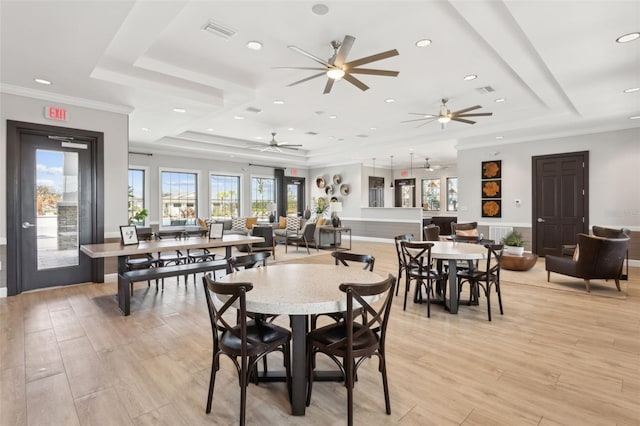 dining space with a raised ceiling, crown molding, and light hardwood / wood-style flooring