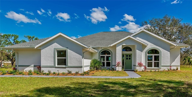 single story home featuring roof with shingles, a front lawn, and stucco siding