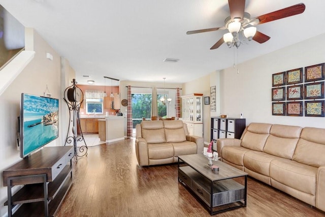 living room with ceiling fan with notable chandelier and hardwood / wood-style floors