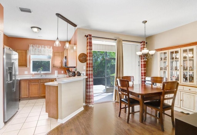 dining room with an inviting chandelier, plenty of natural light, sink, and light wood-type flooring