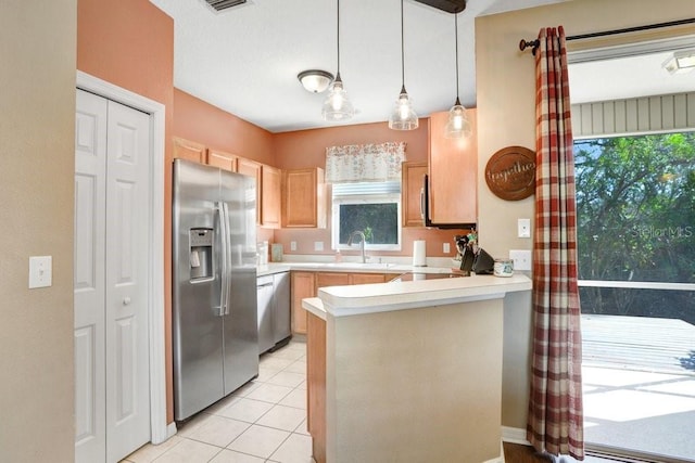 kitchen with light brown cabinetry, sink, kitchen peninsula, pendant lighting, and stainless steel appliances