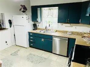 kitchen featuring sink, blue cabinetry, dishwasher, and white fridge