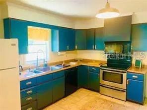 kitchen with pendant lighting, sink, white fridge, light tile patterned floors, and electric stove