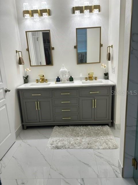 bathroom featuring marble finish floor, a sink, and double vanity