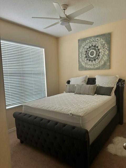 carpeted bedroom with a ceiling fan and baseboards