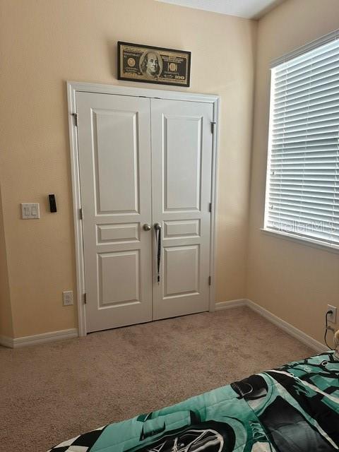 unfurnished bedroom with light carpet, a closet, and baseboards