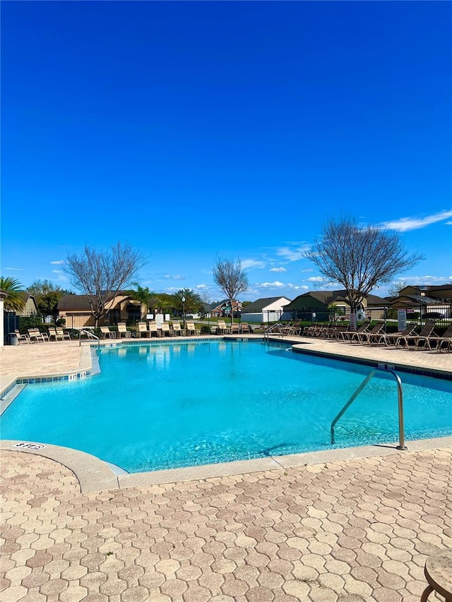 community pool with a patio area and fence