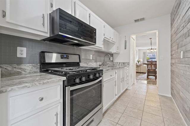 kitchen with sink, backsplash, light stone counters, white cabinets, and gas range