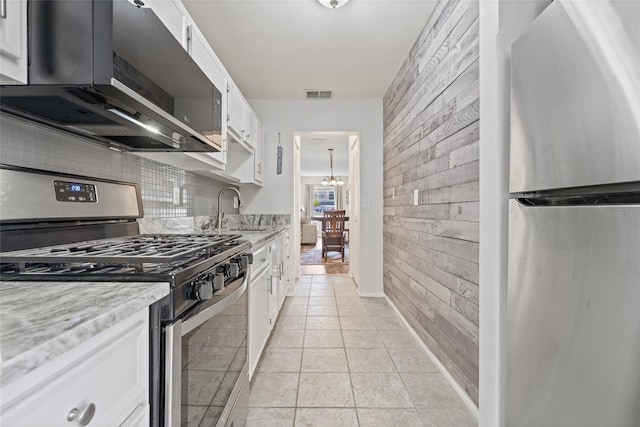 kitchen with stainless steel appliances, white cabinetry, sink, and backsplash