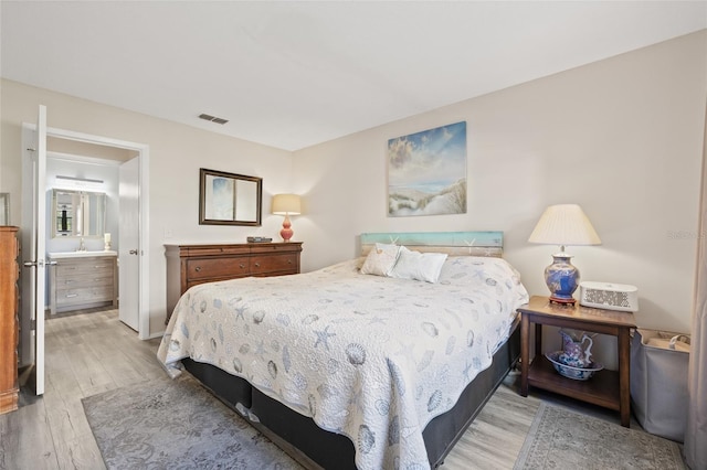 bedroom featuring ensuite bathroom and light wood-type flooring