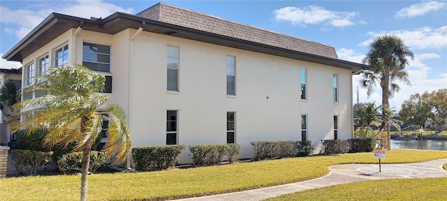 view of property exterior with a water view and a yard