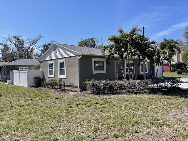 view of property exterior with a garage, stucco siding, fence, and a yard