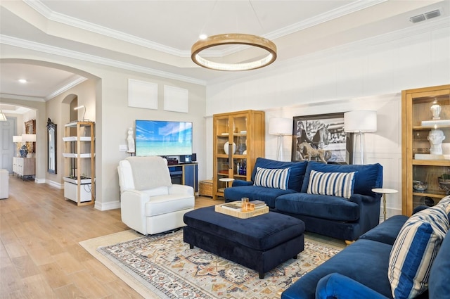 living room with crown molding, hardwood / wood-style floors, and a tray ceiling