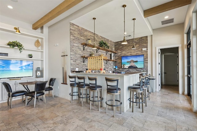 kitchen featuring brick wall, beamed ceiling, a breakfast bar area, hanging light fixtures, and kitchen peninsula