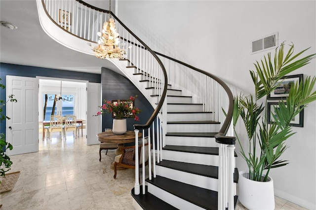 staircase with a towering ceiling and a notable chandelier