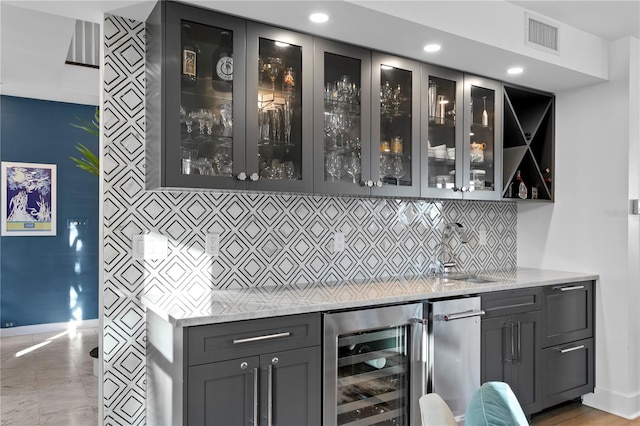 bar featuring light stone countertops, sink, wine cooler, and backsplash