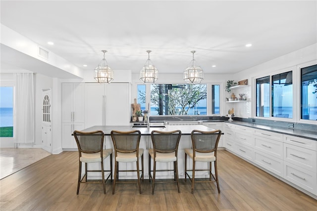 kitchen with white cabinetry, decorative light fixtures, a kitchen breakfast bar, and a kitchen island