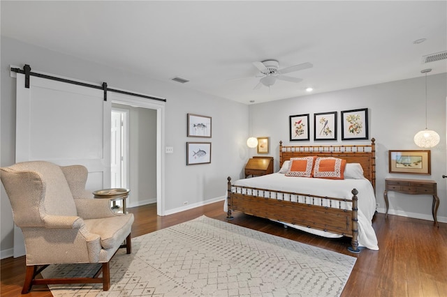 bedroom with ceiling fan, a barn door, and hardwood / wood-style floors