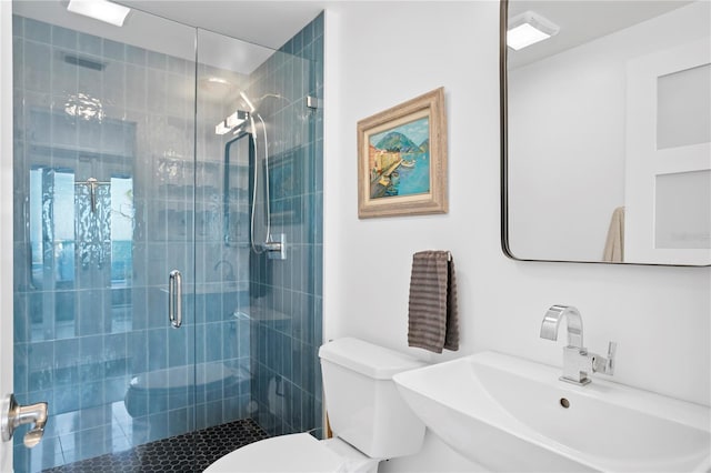 bathroom featuring a shower with shower door, sink, and toilet