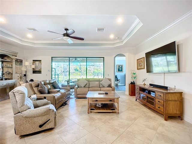 living room featuring light tile patterned flooring, ceiling fan, ornamental molding, and a tray ceiling