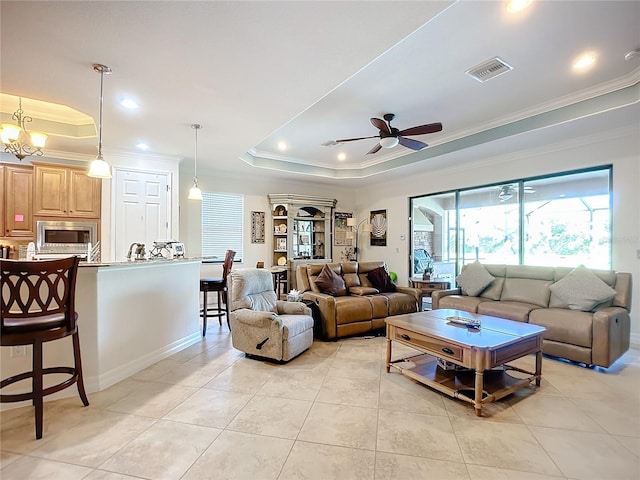 living room featuring crown molding, light tile patterned floors, a tray ceiling, and ceiling fan with notable chandelier