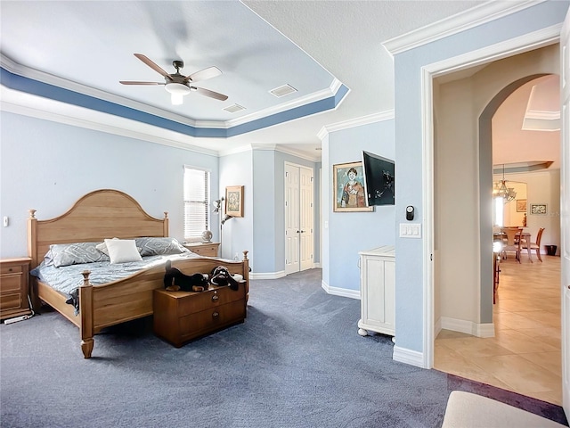 bedroom with a tray ceiling, ornamental molding, ceiling fan, and carpet